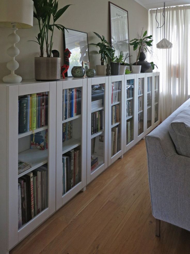 a living room filled with lots of furniture and bookshelves next to a window