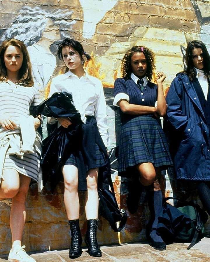 four young women standing next to each other in front of a wall