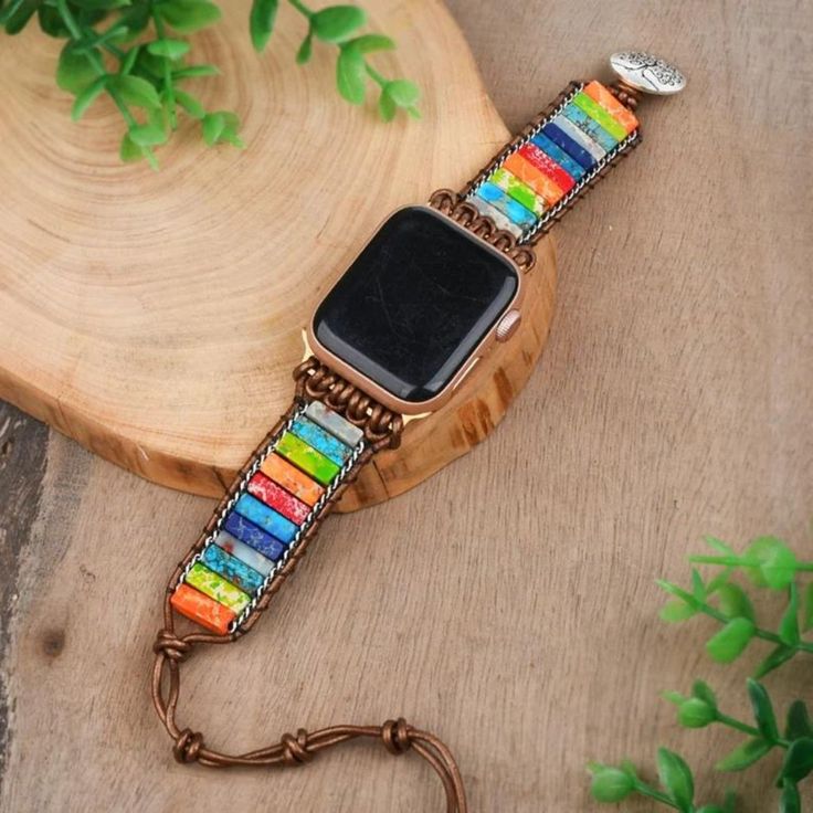 an apple watch bracelet with multicolored glass beads and a metal clasp on a wooden surface