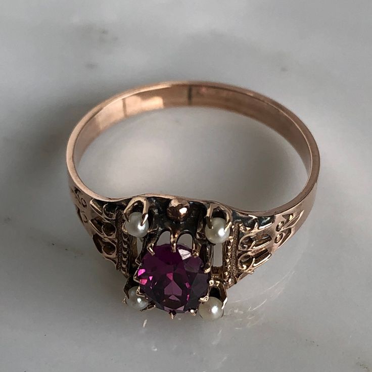 Details: Beautiful Victorian Garnet and Seed Pearl ring set in lovely 14K rose gold. The band is adorned in lovely abstract filigree engraving. The stone has great depth, and has a lovely rich pink tint to the garnet. It is surrounded by 4 seed pearls. The garnet measures 7.5mm x 5mm. There are no internal markings. Measurements: Ring measures a size 7 3/4 US. It can be re-sized for a fee. Condition: The overall all condition of this ring is very good. Please ask all questions prior to placing a Oval Rose Gold Ruby Ring With Rose Cut Diamonds, Elegant Rose Gold Engraved Ring, Ornate 14k Gold Ruby Ring For Anniversary, Victorian Rose Gold Ruby Ring, Fine Jewelry Rose Gold Rings Stamped 14k, Elegant Rose Gold Engraved Ring Stamped 14k, Victorian Hallmarked Rose Gold Ruby Ring, Victorian Rose Gold Ruby Ring Hallmarked, Victorian 14k Gold Ruby Ring With Intricate Design