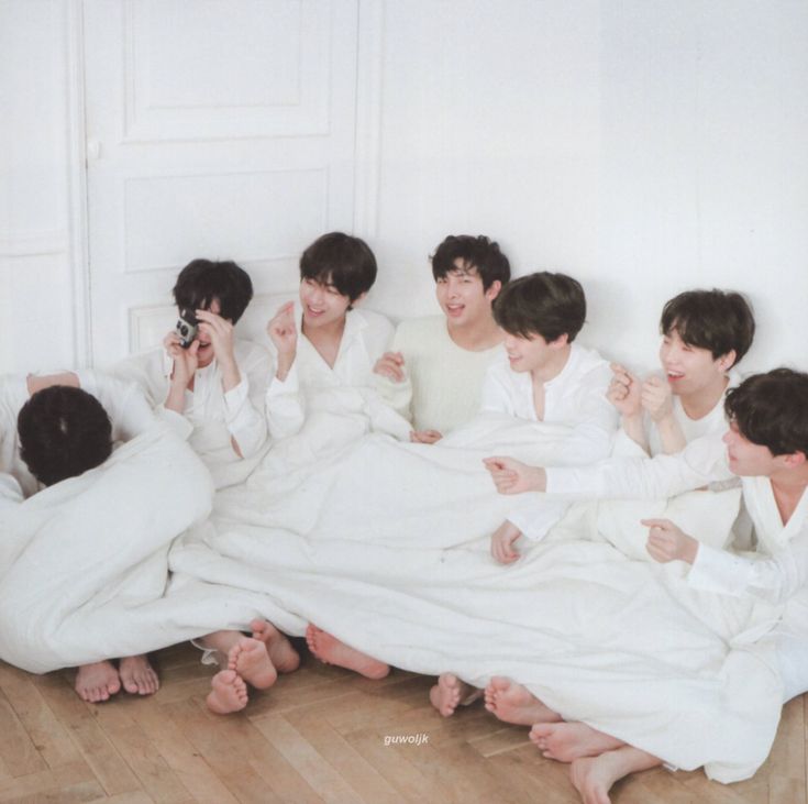 group of young men laying on the floor in white sheets with one person taking a photo