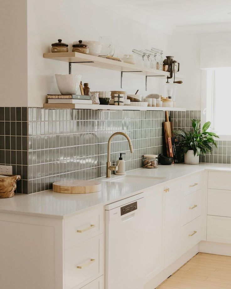 a kitchen with white cabinets and tiled backsplash, wooden shelves above the sink