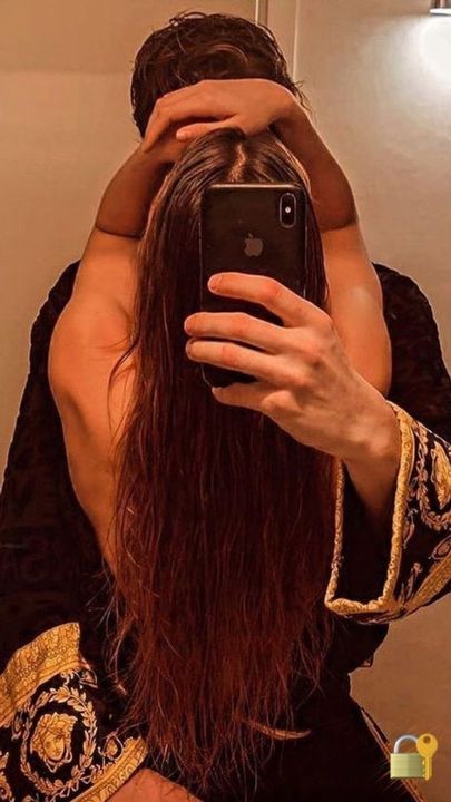 a woman taking a selfie in front of a mirror with her hair pulled back