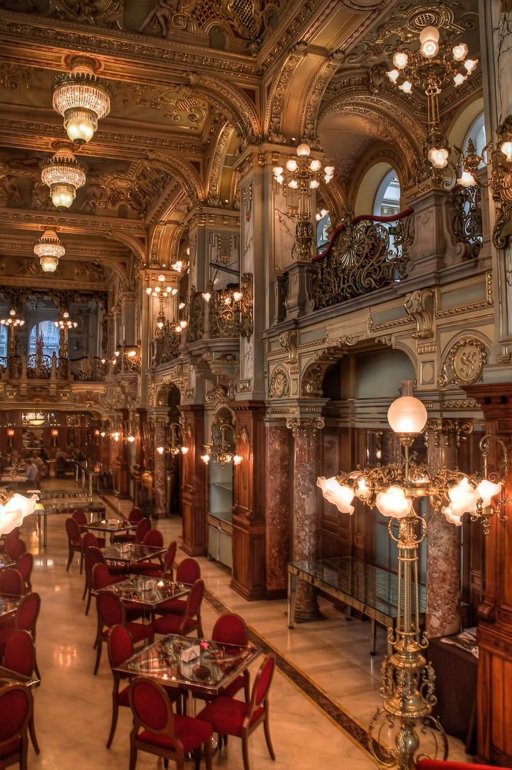 an ornately decorated dining room with chandeliers and tables in the center, along with red chairs