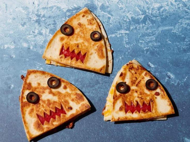 three slices of pizza with faces painted on them, sitting on top of an ice - covered surface