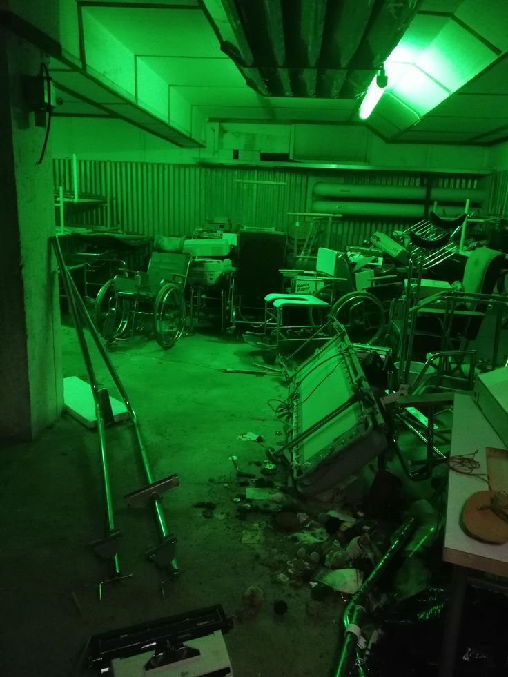 a room filled with lots of junk and green lights on the ceiling is lit up