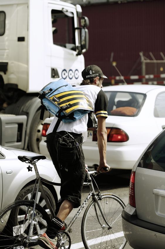 a man riding a bike down a street next to parked cars