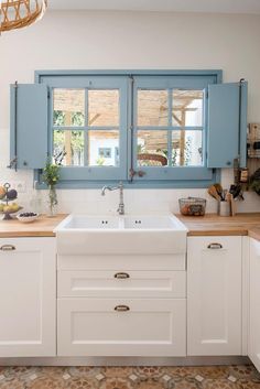 a white kitchen with blue windows and wooden counter tops, along with wood flooring