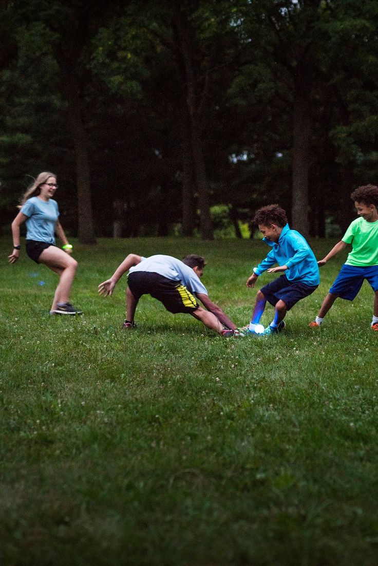 three children are playing with a frisbee in the grass while another child watches