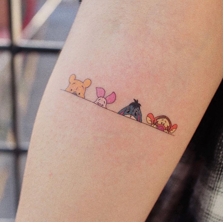 a woman's arm with three cartoon characters on it and one has a small tattoo