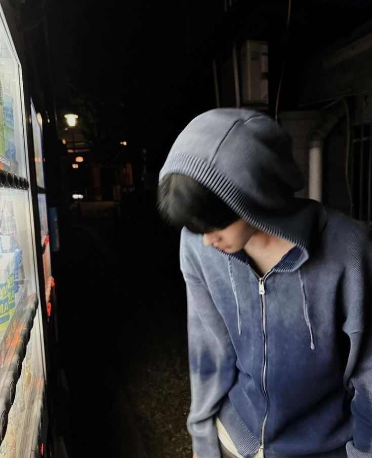 a young man standing next to a wall covered in posters