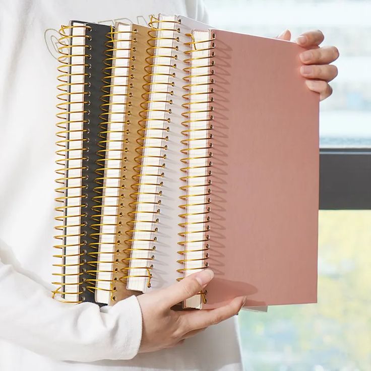 a person holding a spiral notebook in their hands