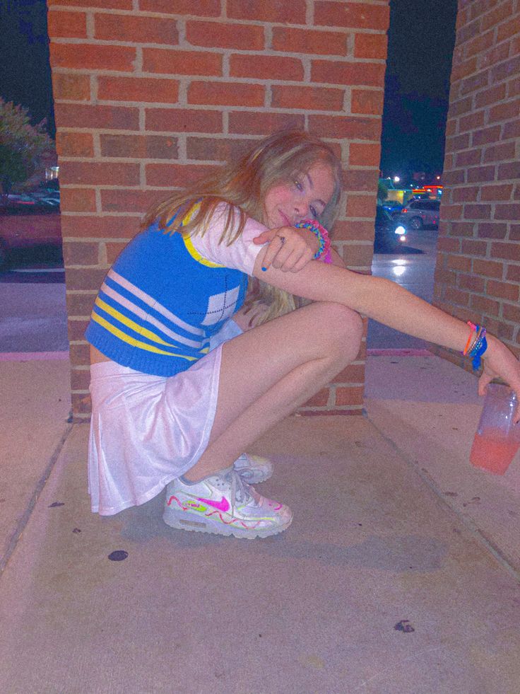 a young woman sitting on the ground with a toothbrush in her mouth