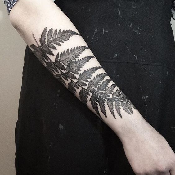 a woman's arm with a fern tattoo on it