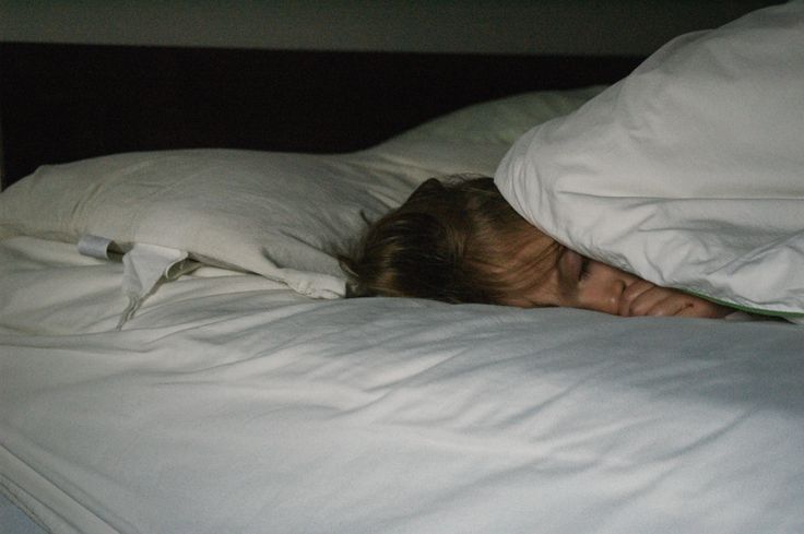 a woman is sleeping in bed with her head under the covers