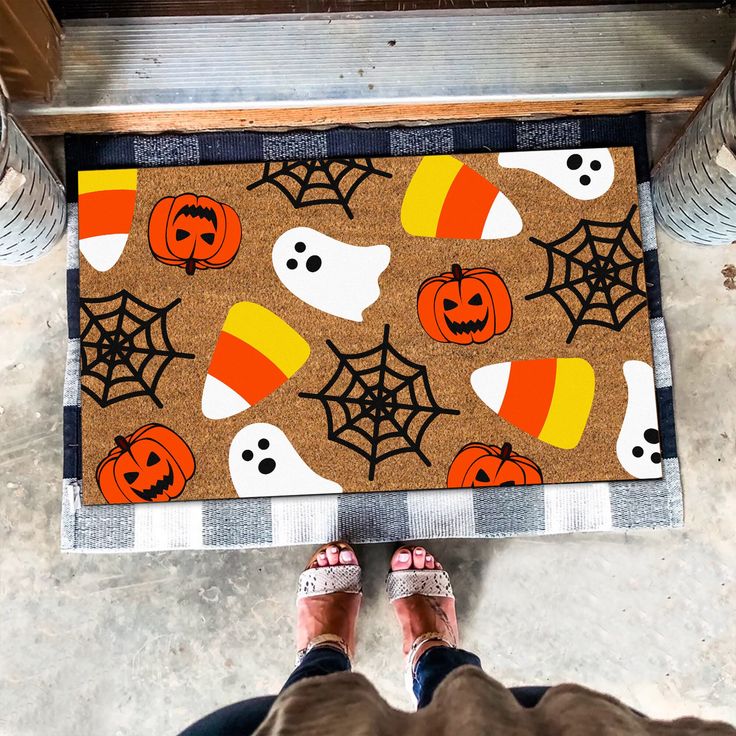 a person standing in front of a door mat with halloween decorations on it