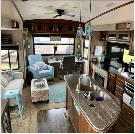 a kitchen and living room inside of a recreational vehicle or rv with wood cabinets, blue chairs, and an island in the middle