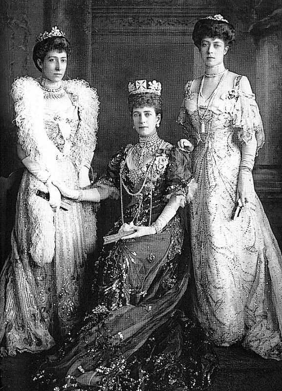 three women in dresses and tiaras posing for a photo