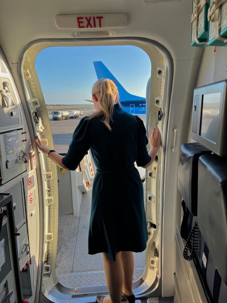 a woman standing in the doorway of an airplane looking out at the tarmacs