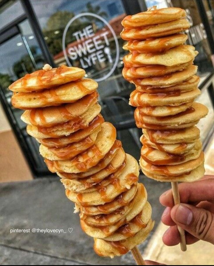 a hand holding a stack of pancakes on a stick