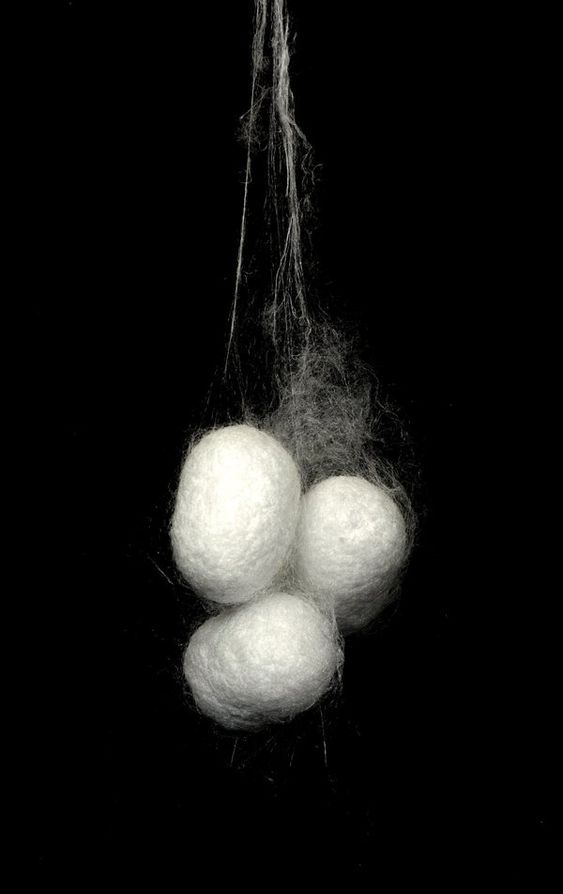 three balls of wool are hanging from a string on a black background with white thread