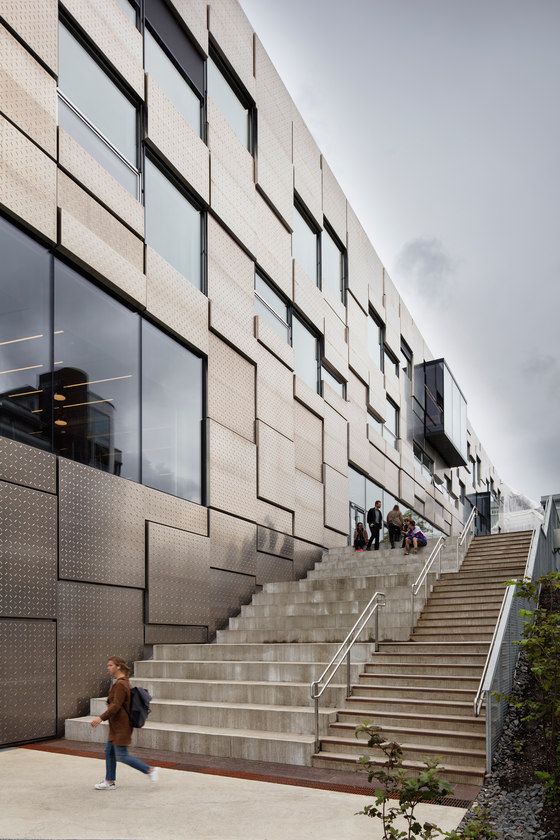 people are walking up and down the stairs in front of a building with many windows