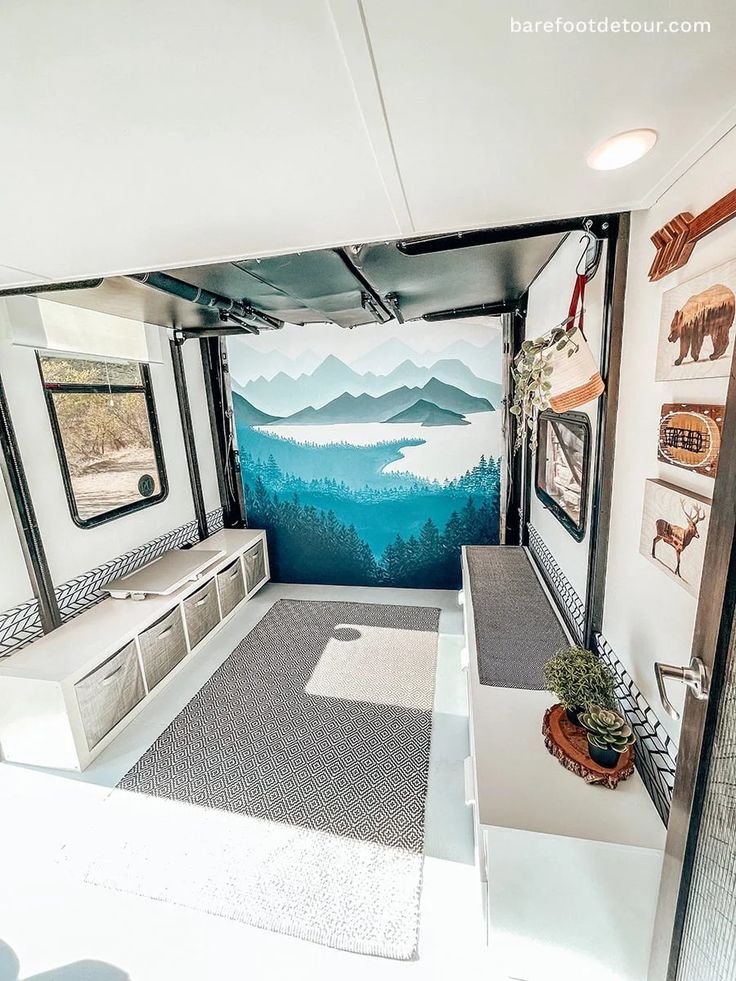 the interior of a camper with mountains painted on the wall and windows in it