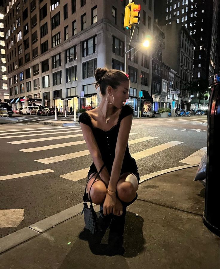 a woman sitting on the side of a street next to a traffic light at night