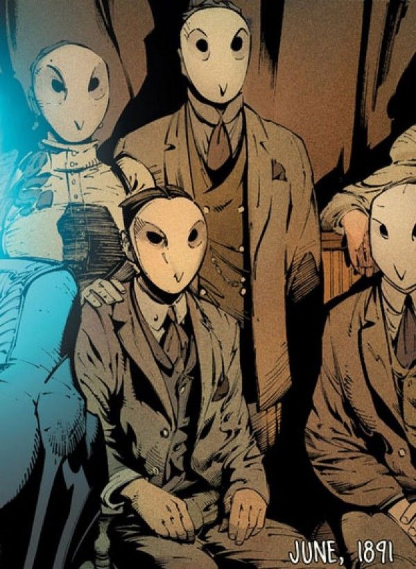 an image of some people sitting in front of two alien heads and one is wearing a suit