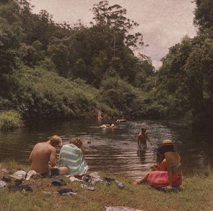 several people are sitting in the water near some trees