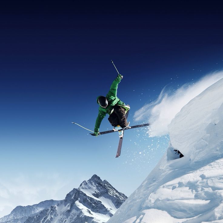 a man flying through the air while riding skis on top of a snow covered mountain