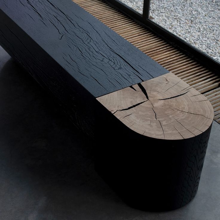 a wooden bench sitting on top of a cement floor next to a metal rail and window