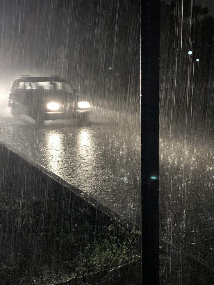 a car is driving through the rain at night