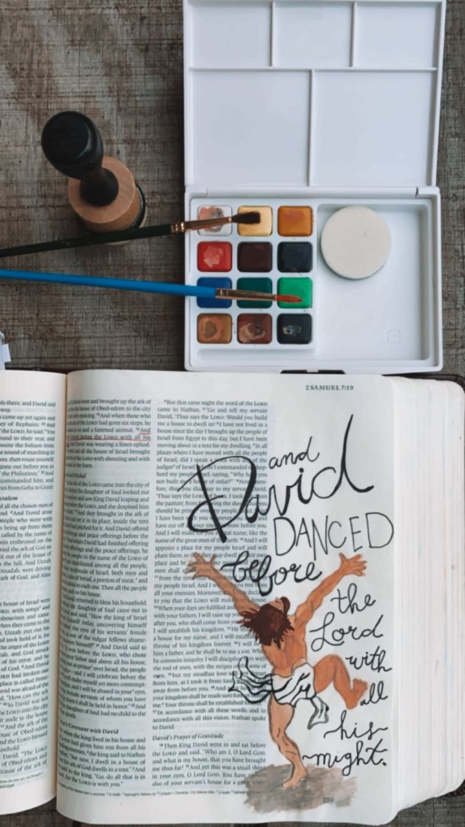 an open book sitting on top of a table next to watercolor paints and brushes