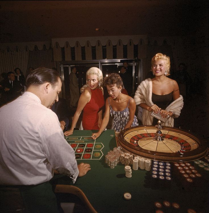 three women and two men playing crap at a casino table