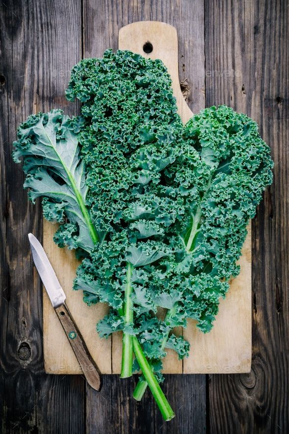 a cutting board topped with green vegetables next to a knife