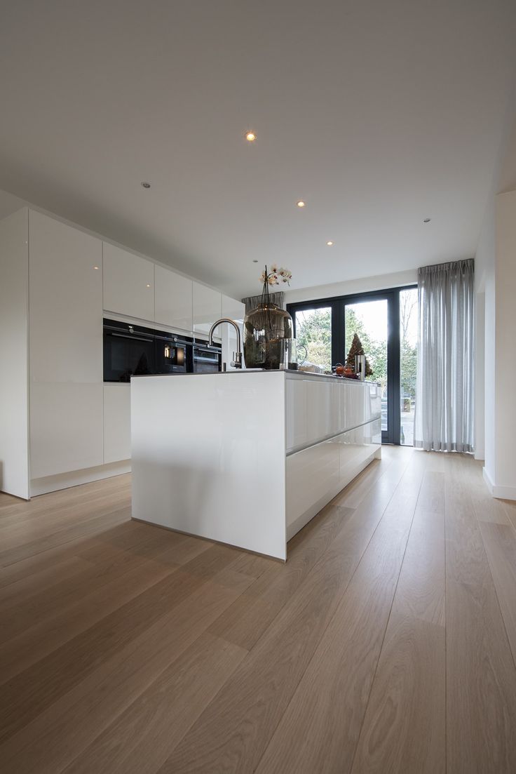 an empty kitchen with white cabinets and wood flooring is seen in this image from the living room