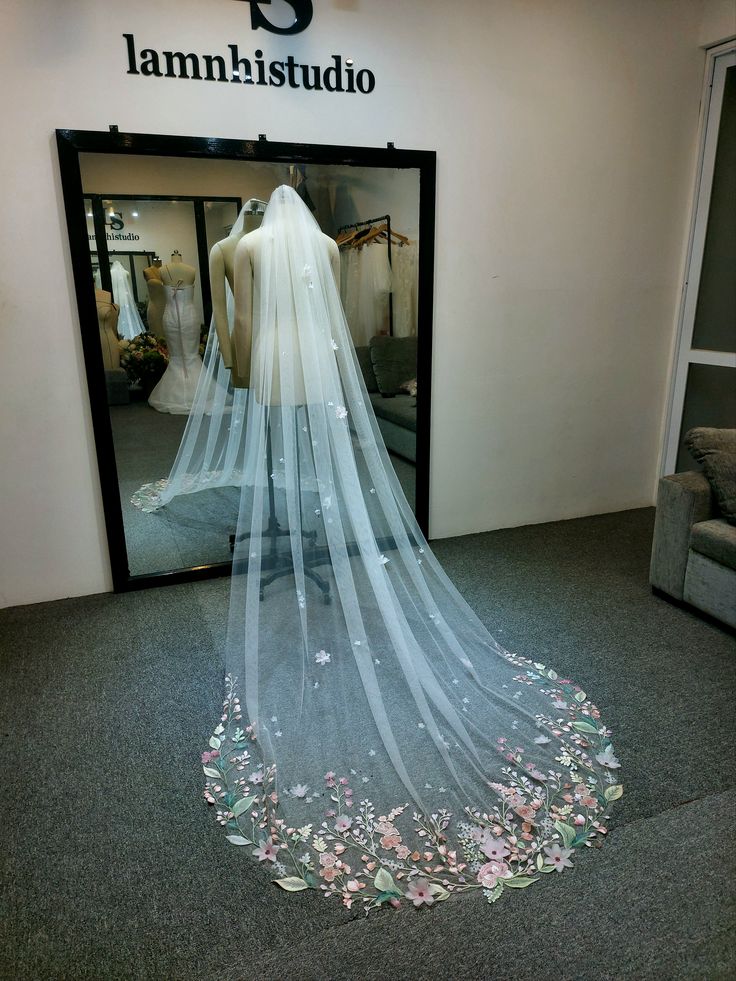 a wedding dress is displayed in front of a mirror with flowers all over the floor