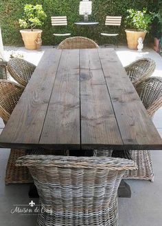 an outdoor table with wicker chairs around it