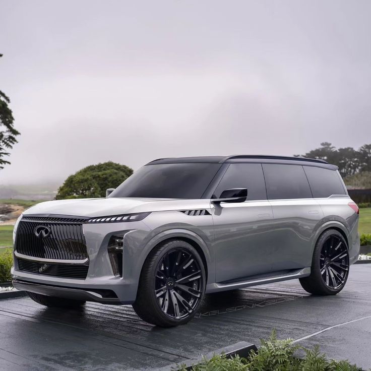 the new infiniti concept suv is parked on a wet parking lot with trees and bushes behind it