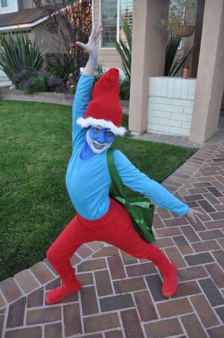 a child dressed in an elf costume standing on one leg with his arms up and legs spread out