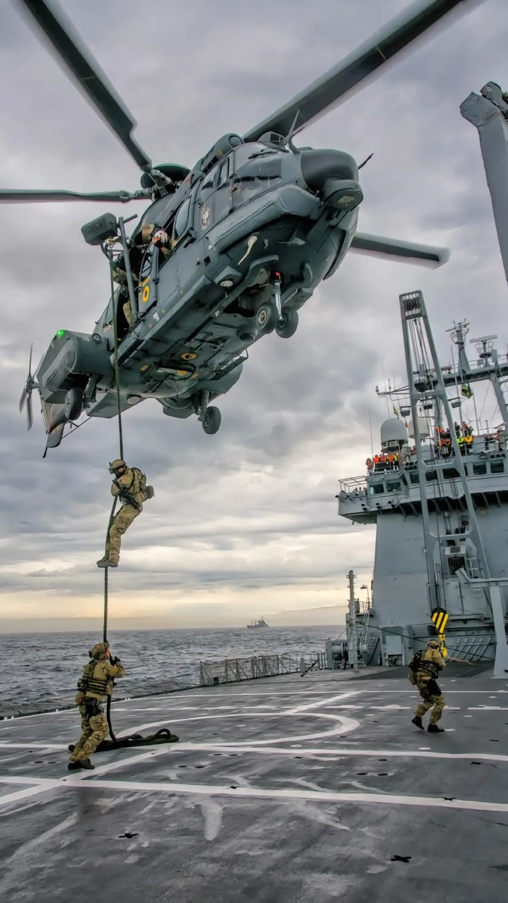 a helicopter that is flying over a ship with people standing on the deck near it