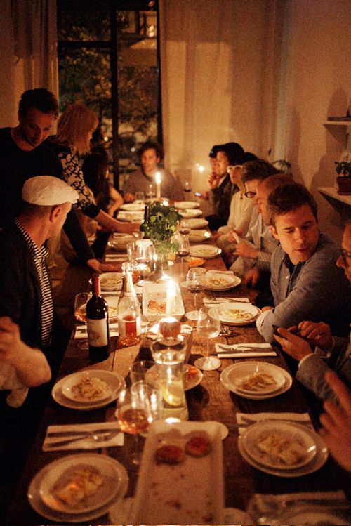 a group of people sitting at a long table with plates of food in front of them