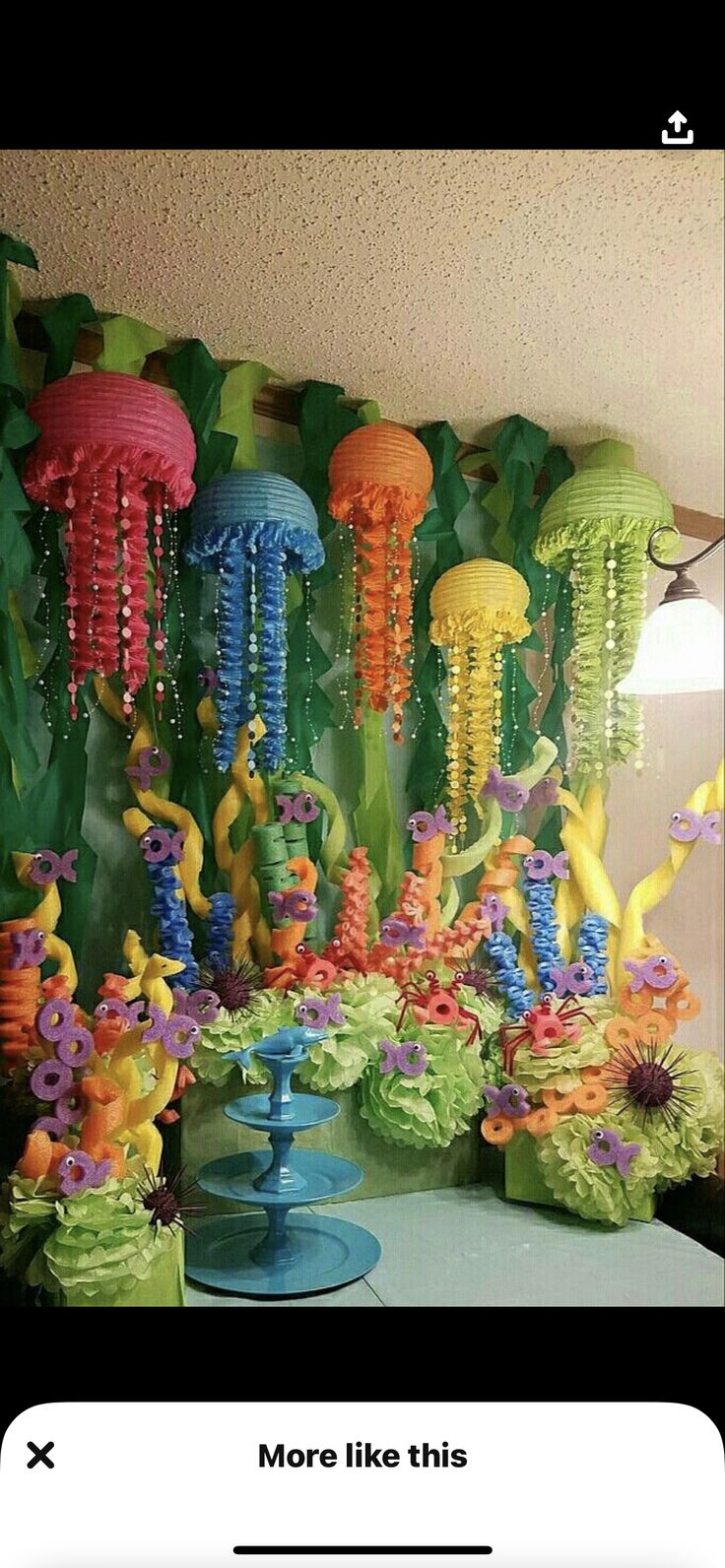 a table topped with vases filled with colorful flowers and jellyfishes hanging from the ceiling