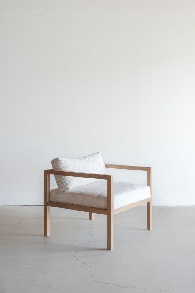 a white chair sitting on top of a cement floor next to a wooden frame wall