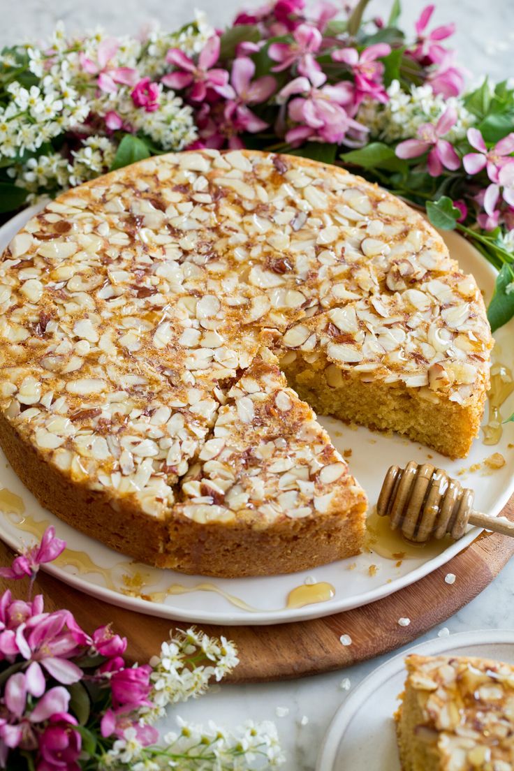 a cake on a plate with a slice missing from it and flowers in the background