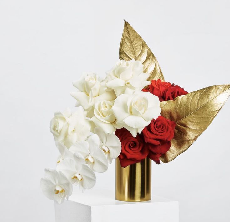 a gold vase with red and white flowers in it