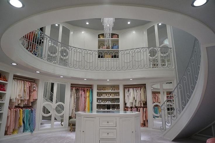 the inside of a large closet with lots of clothes on shelves and drawers in it