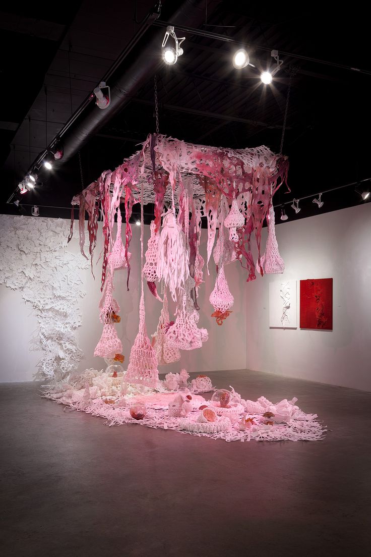 an art installation with pink paper hanging from it's ceiling and lights on the ceiling