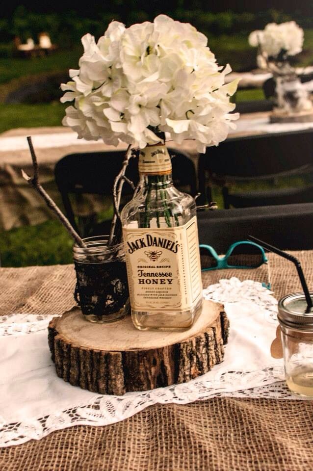 a table topped with a glass bottle filled with white flowers next to a mason jar